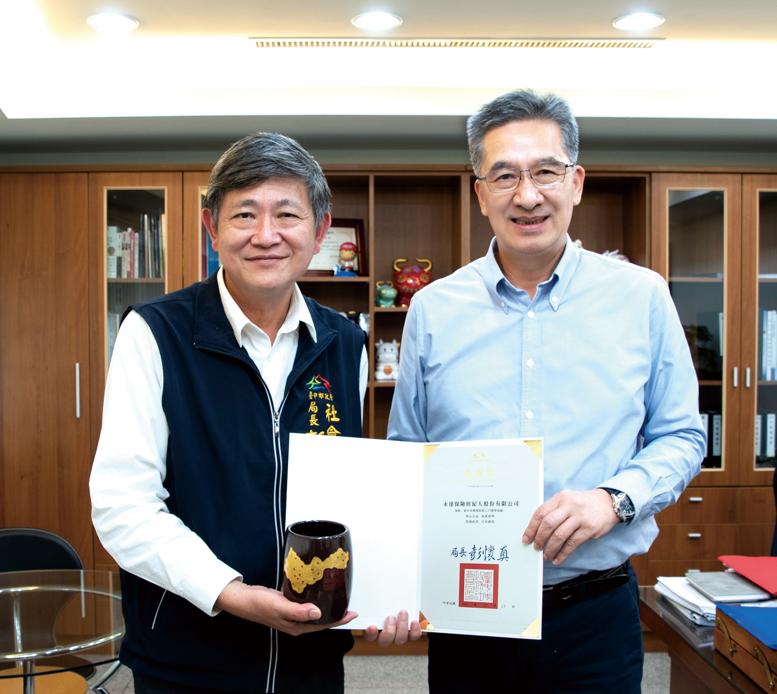 台中市政府社會局彭懷真局長(左)贈送感謝狀，由永達陳慶鴻總經理(右)代表受贈。