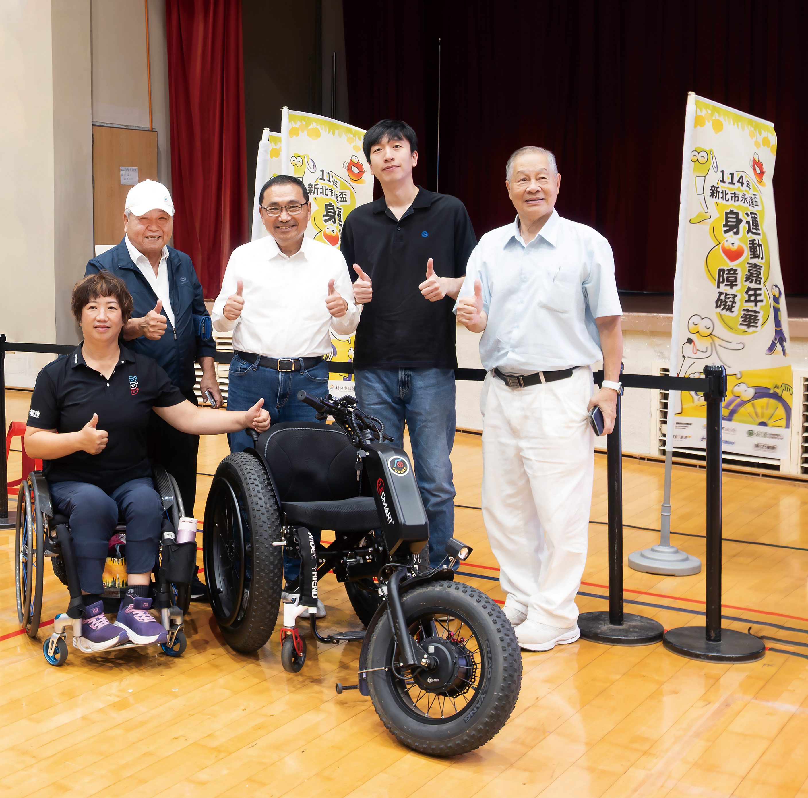 侯友宜市長（中）、吳柏瑨總經理特助（右2）、呂嘉儀營運長（左1）、中華民國身心障礙者休閒運動推廣協會劉耀台副理事長（左2）、張思敏名譽理事長（右1）與本次捐贈的沙灘輪椅合影留念。