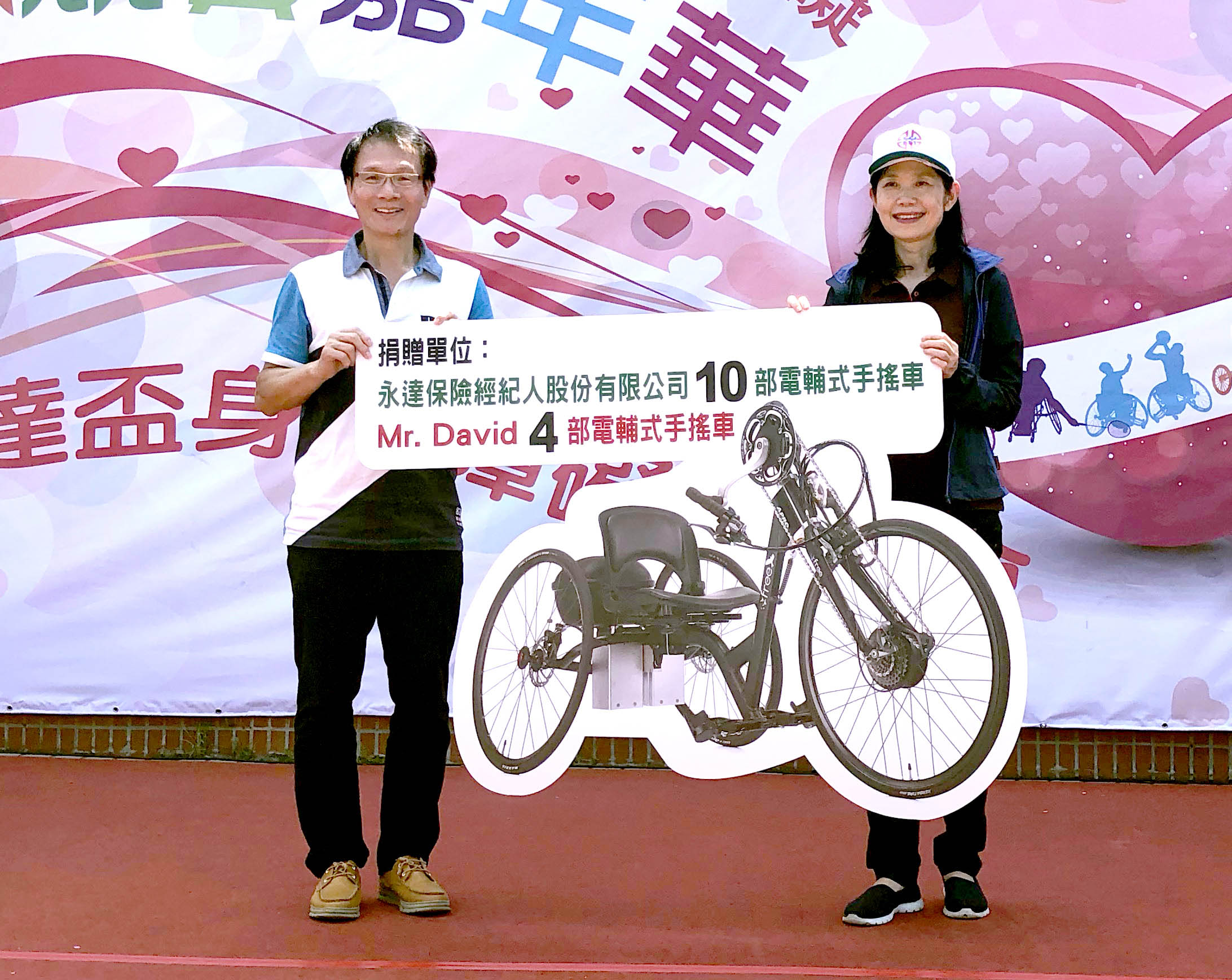 永達保經李忠約副總(圖左)代表捐贈10輛電輔式手搖自行車，由新北市呂衛青副市長（圖右）代表受贈。