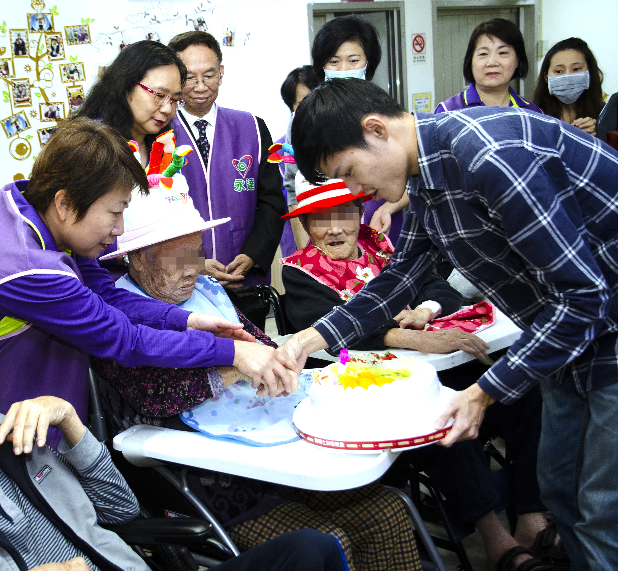 永達志工協助十二月壽星長輩切蛋糕。