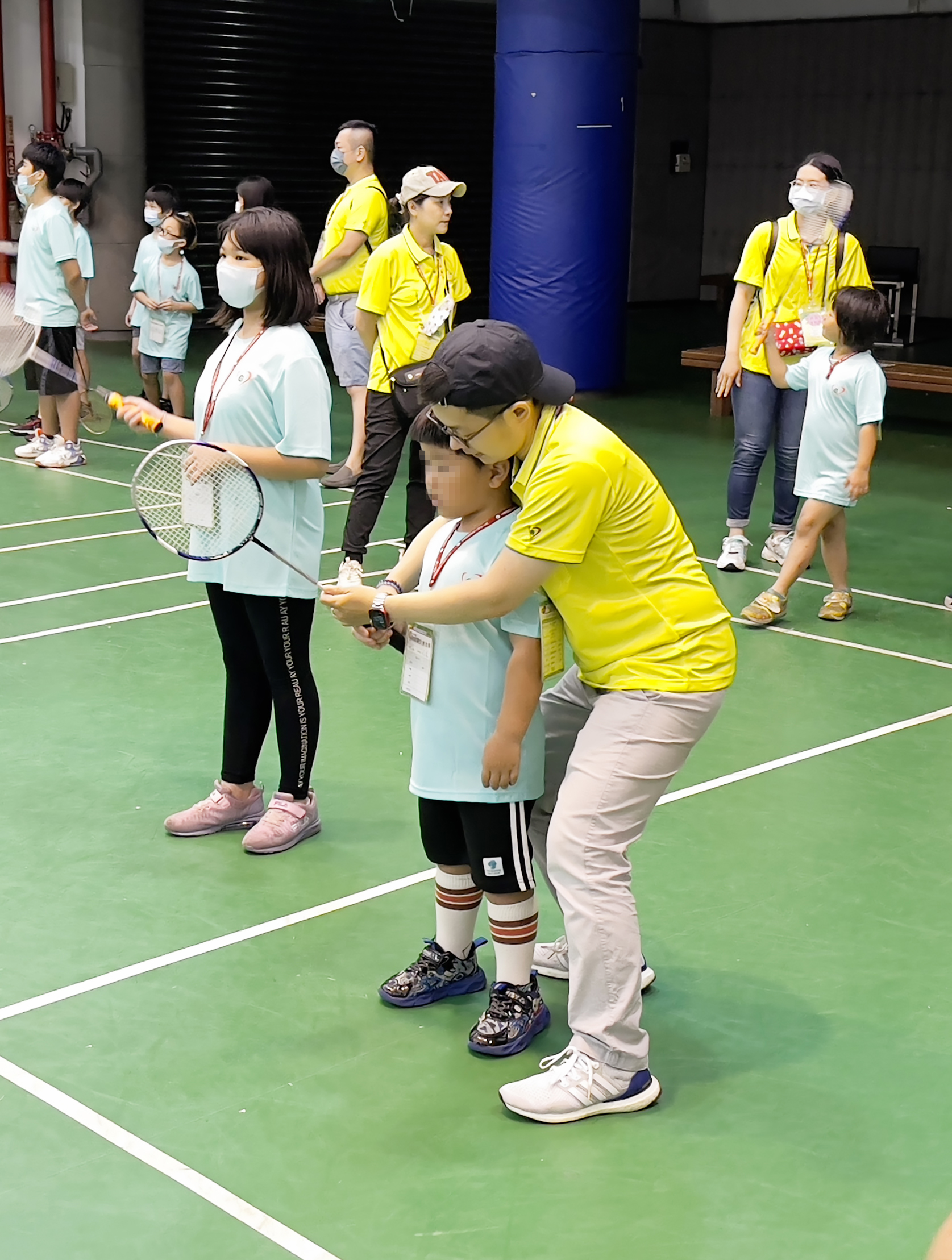 永達志工用愛心和耐心陪伴弱勢孩童練習羽球。