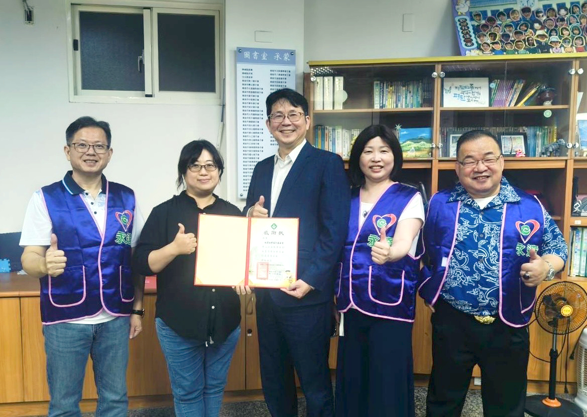 高雄市紅十字會育幼中心林瑛凰院長(左2)頒贈感謝狀，由永達保經高文山業務副總(中)代表受贈，與陳慧雯業務籌備副總(右2)、蔡明宏業務協理(左1)、張富強業務籌備協理(右1)合影留念。