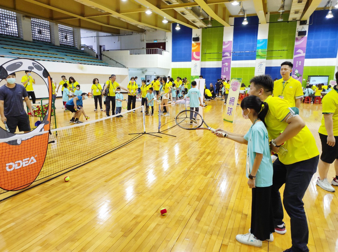 志工手把手的教導寶貝練習網球。