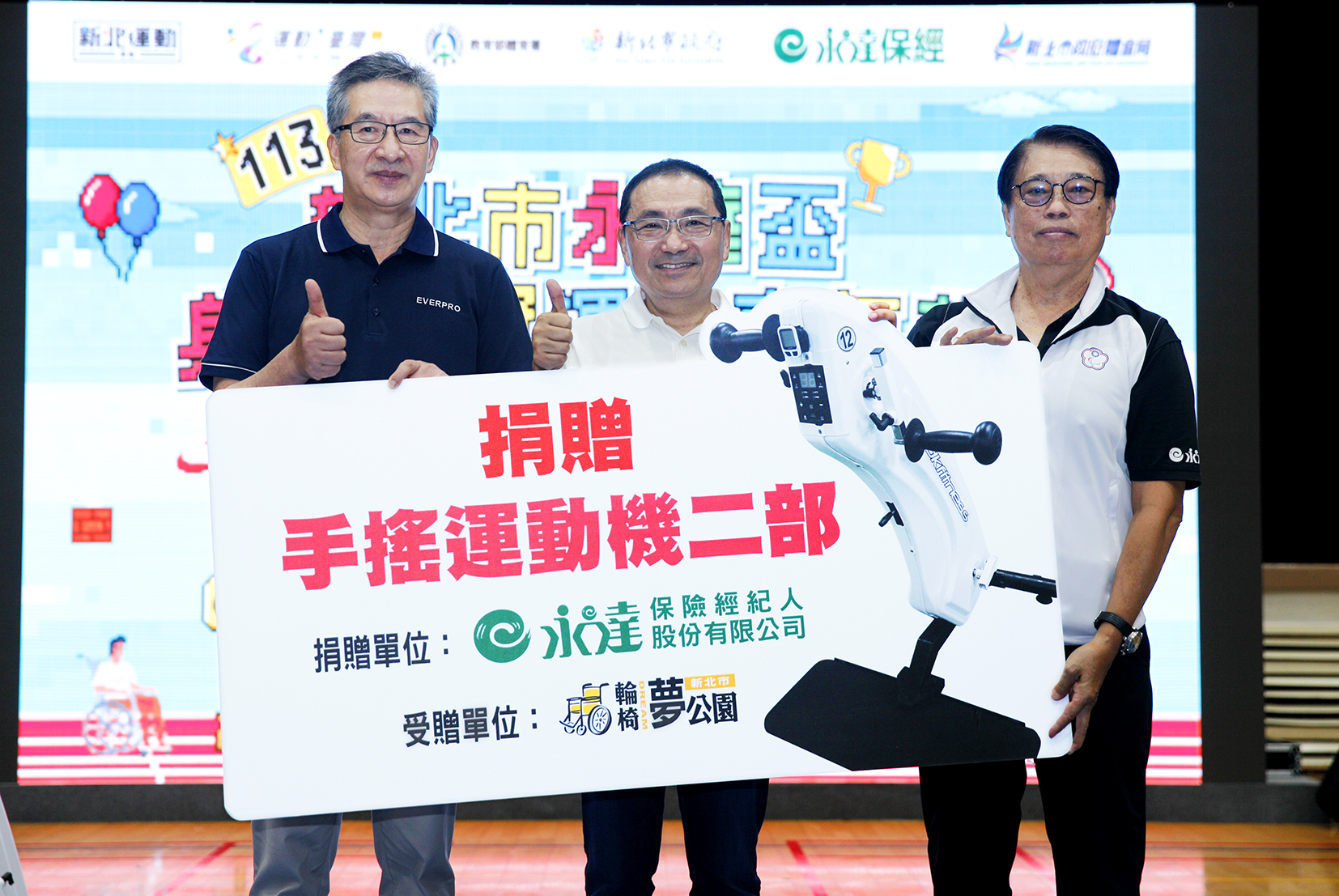 永達保經捐贈兩台手搖運動機,(左起)由陳慶鴻總經理代表捐贈、新北市政府侯友宜市長見證、中華民國身心障礙者休閒運動推廣協會林永華理事長代表受贈。
