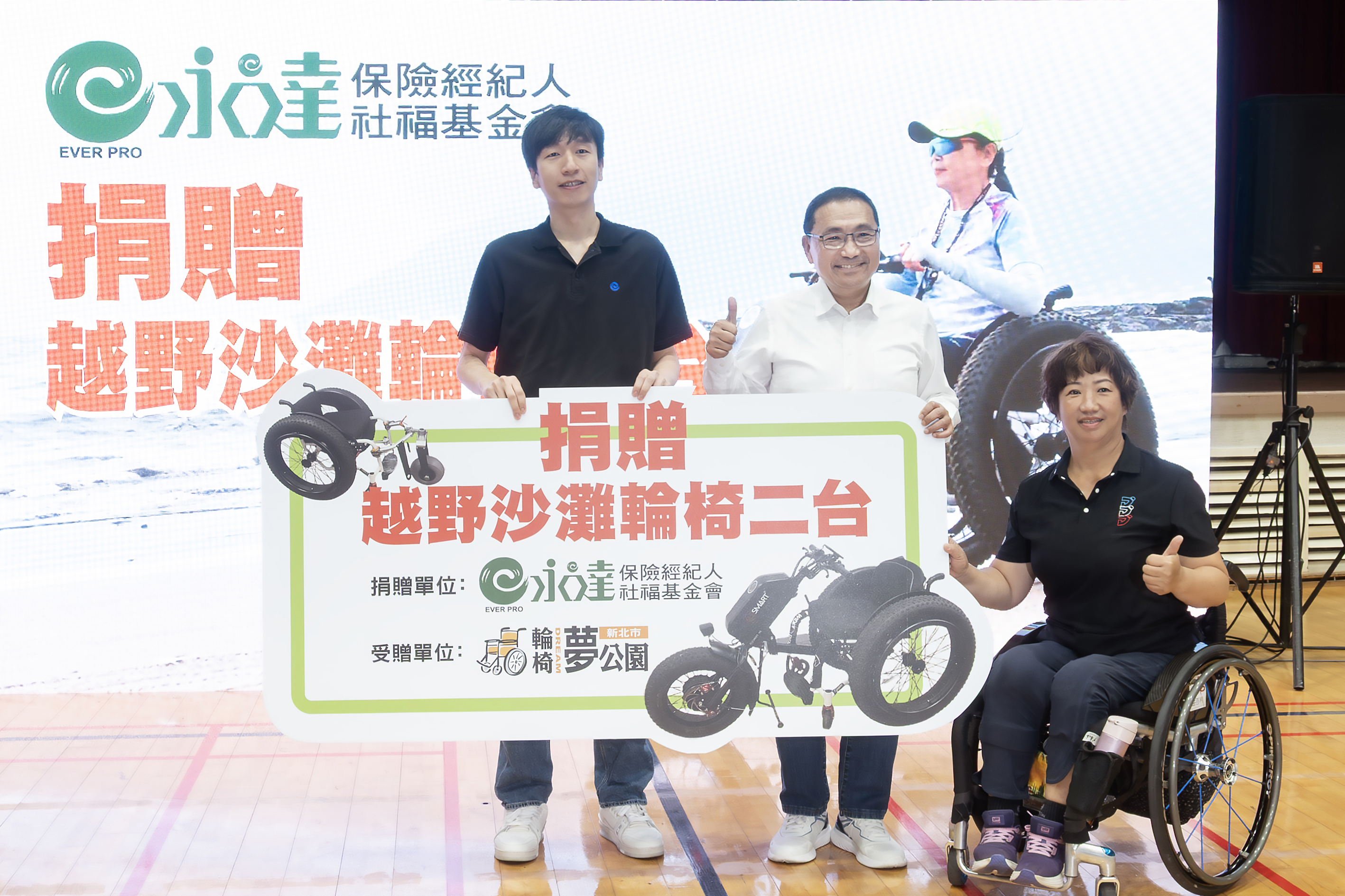 永達保經購置兩台越野沙灘輪椅，由（左起）吳柏瑨總經理特助代表捐贈、新北市政府侯友宜市長見證、輪椅夢公園聯盟呂嘉儀營運長受贈。
